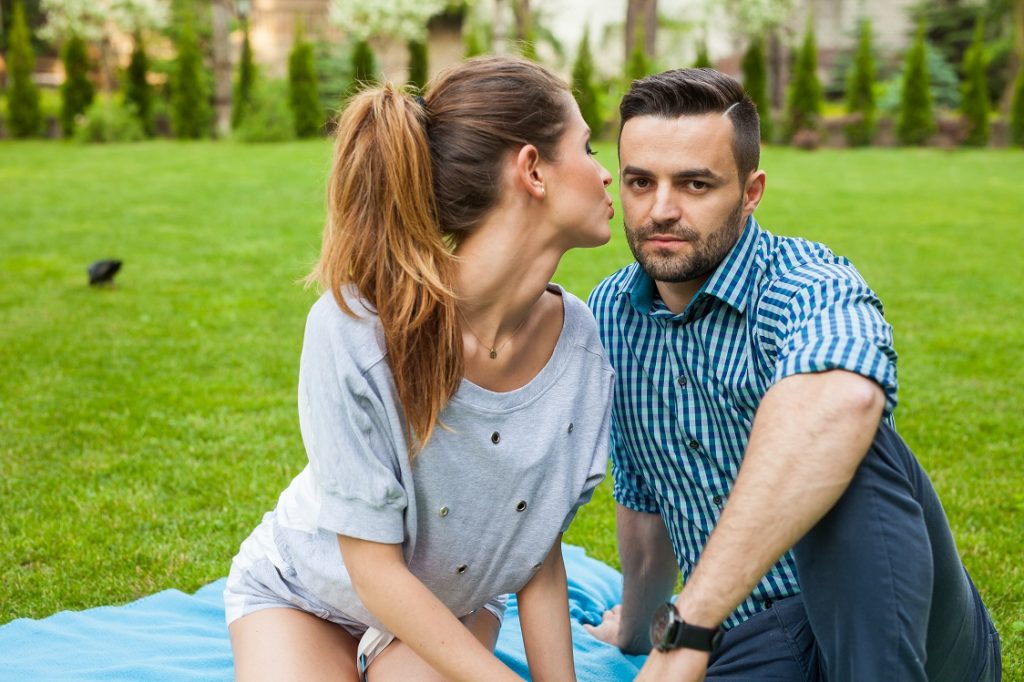 man with woman sitting in park woman about to kiss him
