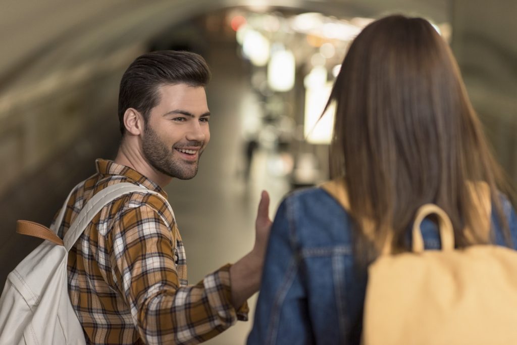 man approaching a girl in a subway in an indirect way
