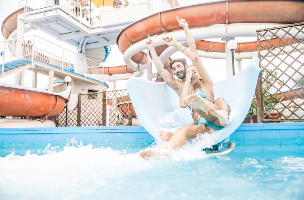guy and girl having lots of fun at an aqua park going down a water slide