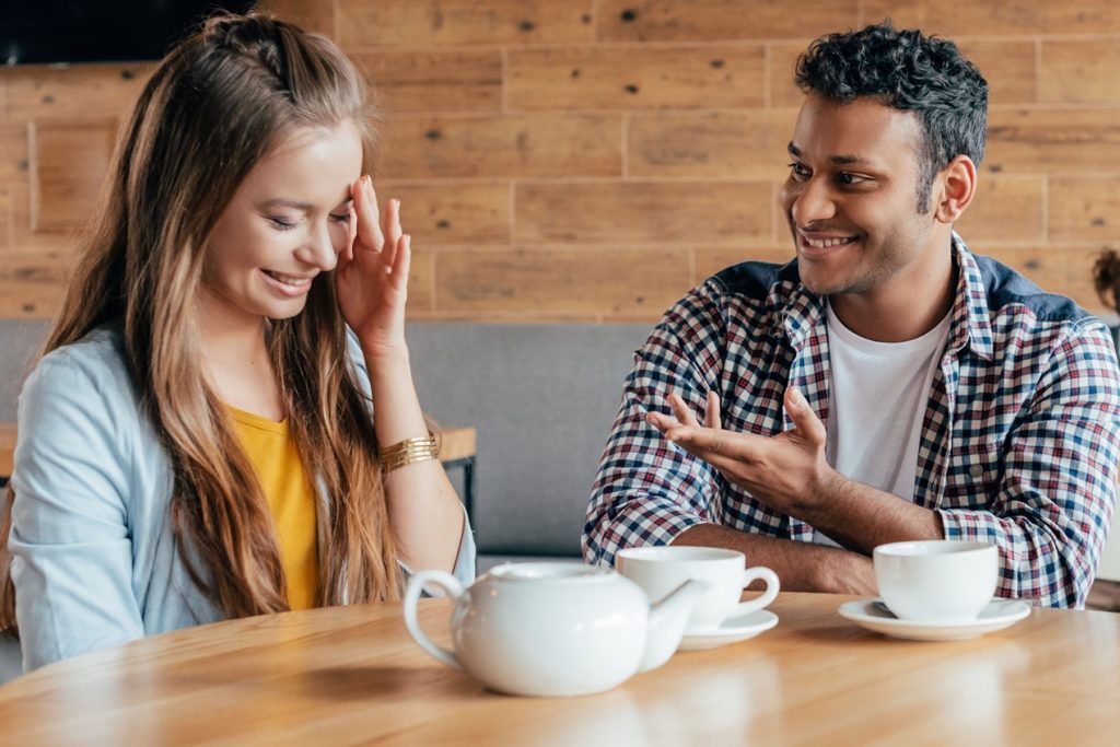 man enjoying himself on a date with a girl, having a blast telling her jokes while she's laughing