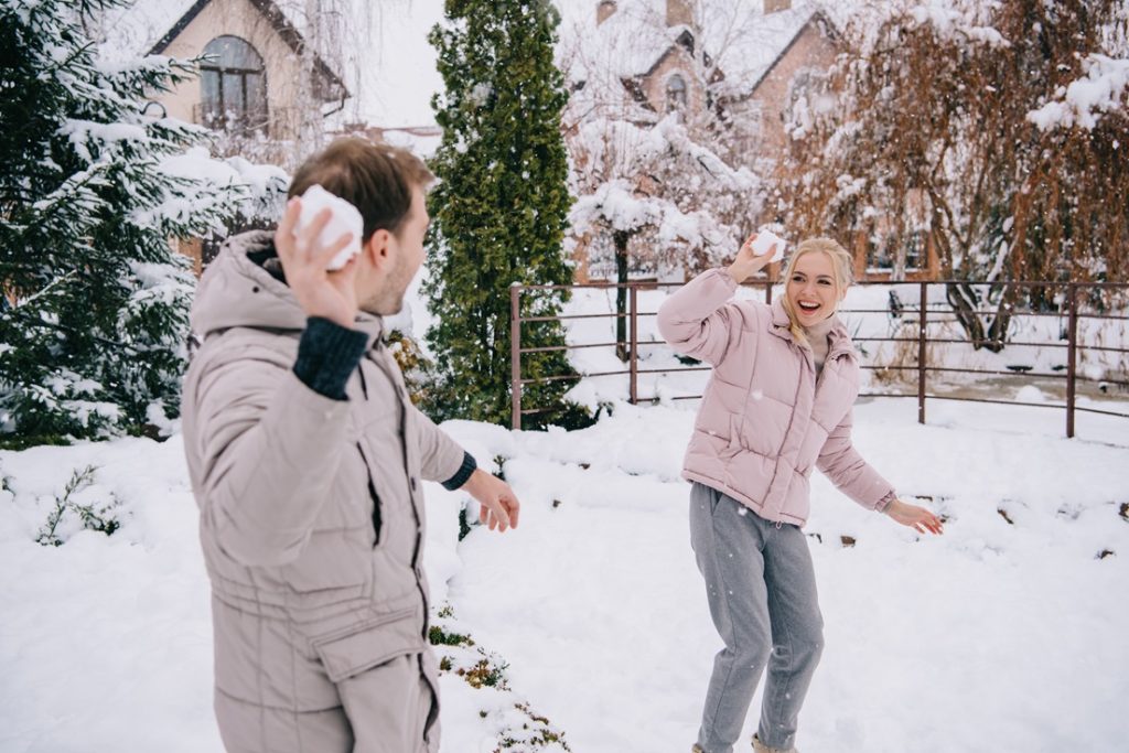man and woman having lots of fun playing a snowball fight